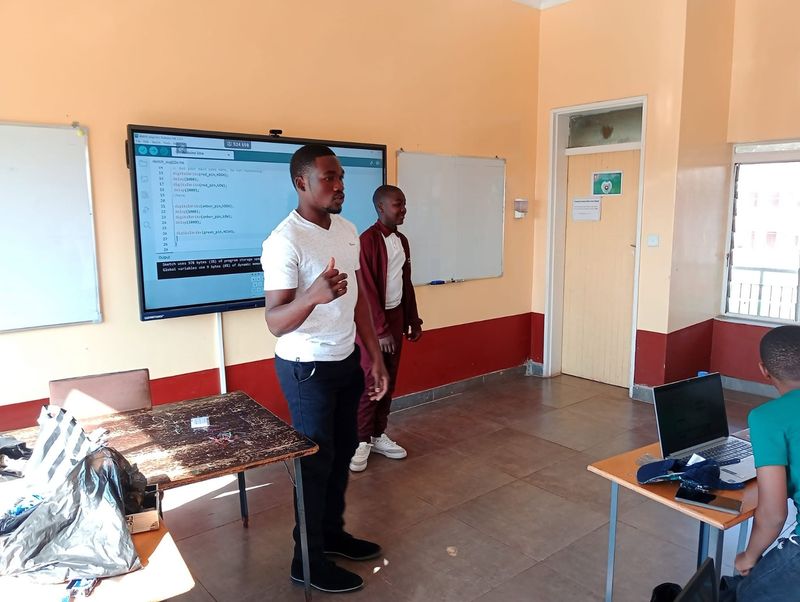 A Mukutronics instructor coaching students through an Arduino coding exercise on a classroom smartboard